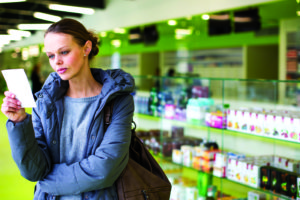60593425 - young woman looking for the right pills in a modern pharmacy (shallow dof; color toned image)